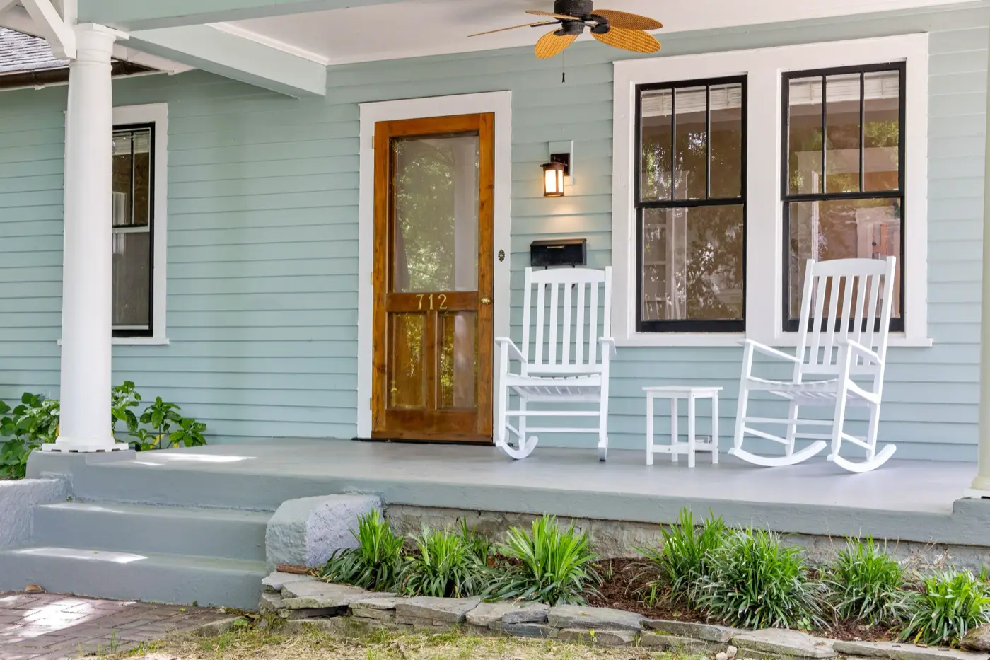 Front porch with white rocking chairs beside a wood front door