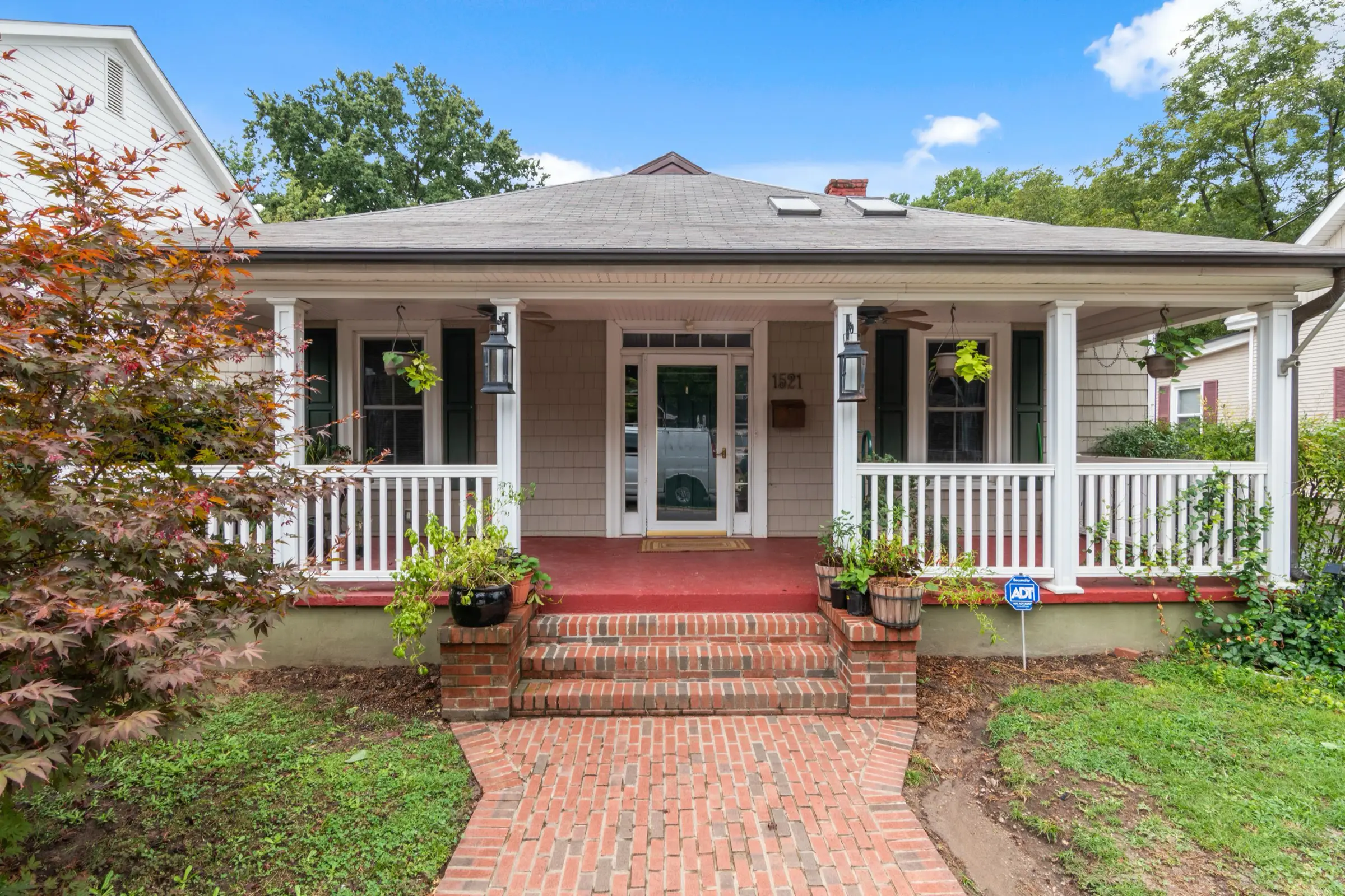 White bungalow with a deep covered front porch and a brick walkway