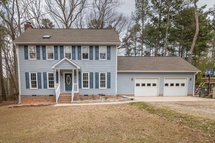 Gray colonial with black shutters and a side two-car garage