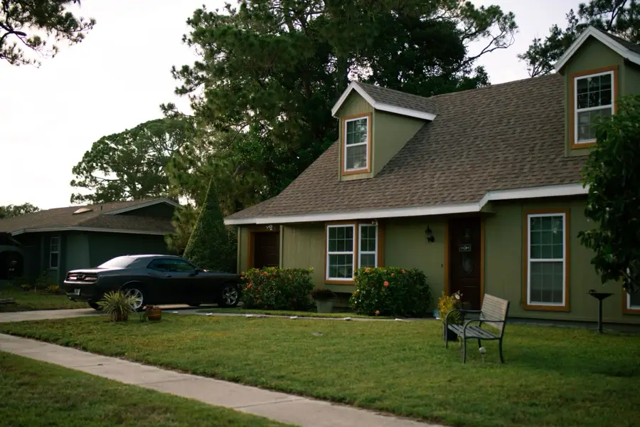 Green cape cod with dormers and a shady front lawn
