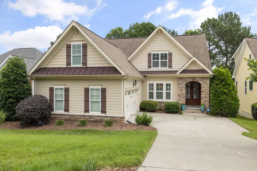 Tan craftsman with a stone entry, arched front door and attached garage