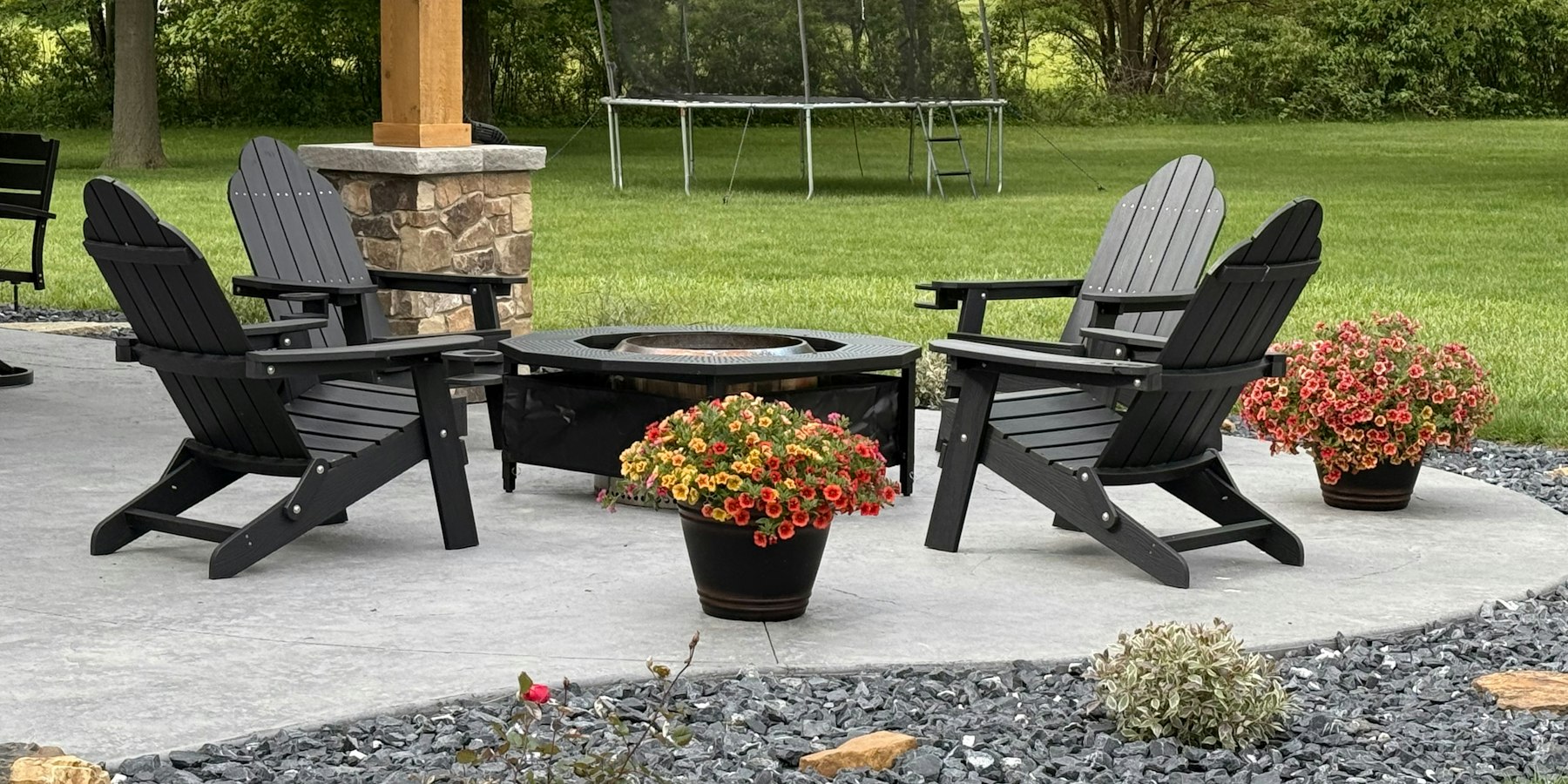 Backyard patio with adirondack chairs, a fire pit, and planted containers